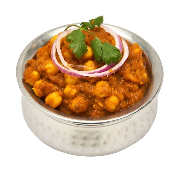 Muna's Chana Masala, a chickpea curry garnished with red onion rings and fresh cilantro in a silver bowl.