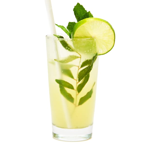 Refreshing Muna Indian drink with curry leaves, mint, lime, and a straw in a tall glass.